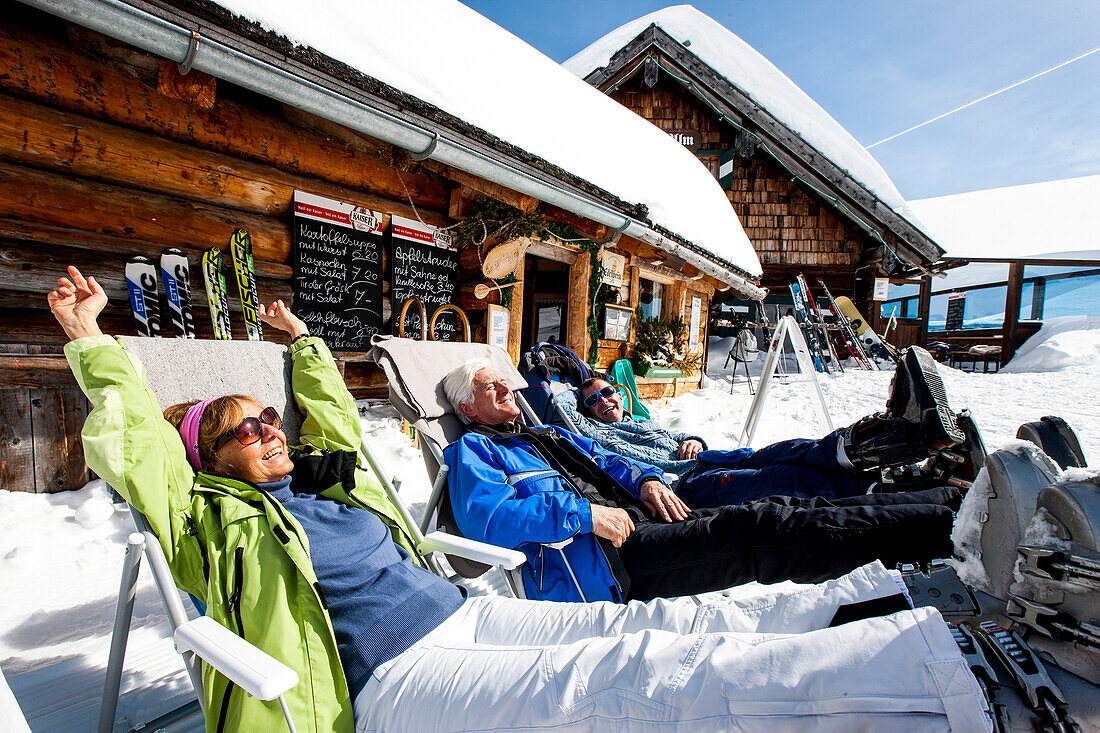 Drei Skifahrer sonnen sich vor einer Skihütte, Fageralm, Salzburg, Österreich