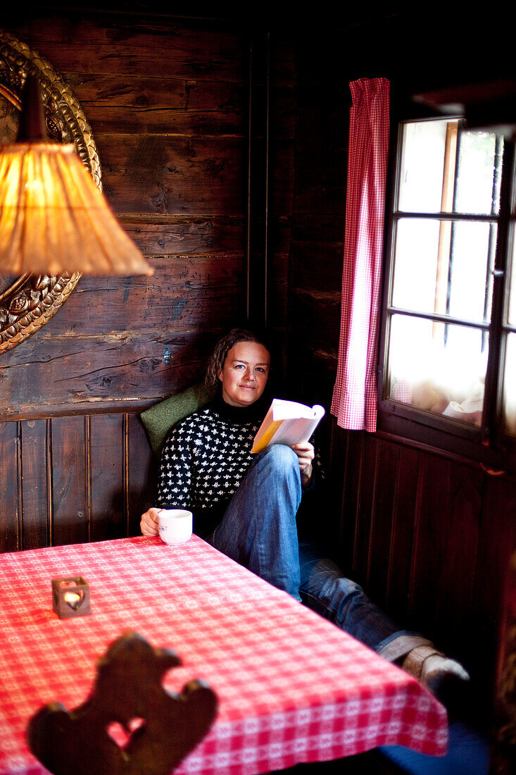 Frau mit einer Tasse Tee ließt ein Buch, Steiermark, Österreich