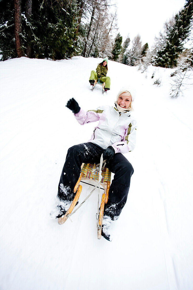 Two young women tobogganing