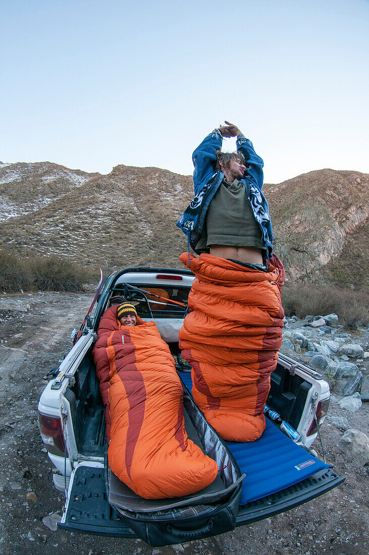 Two men with sleeping bags on off-road vehicle platform, Las Lenas, Mendoza, Cuyo, Argentinia