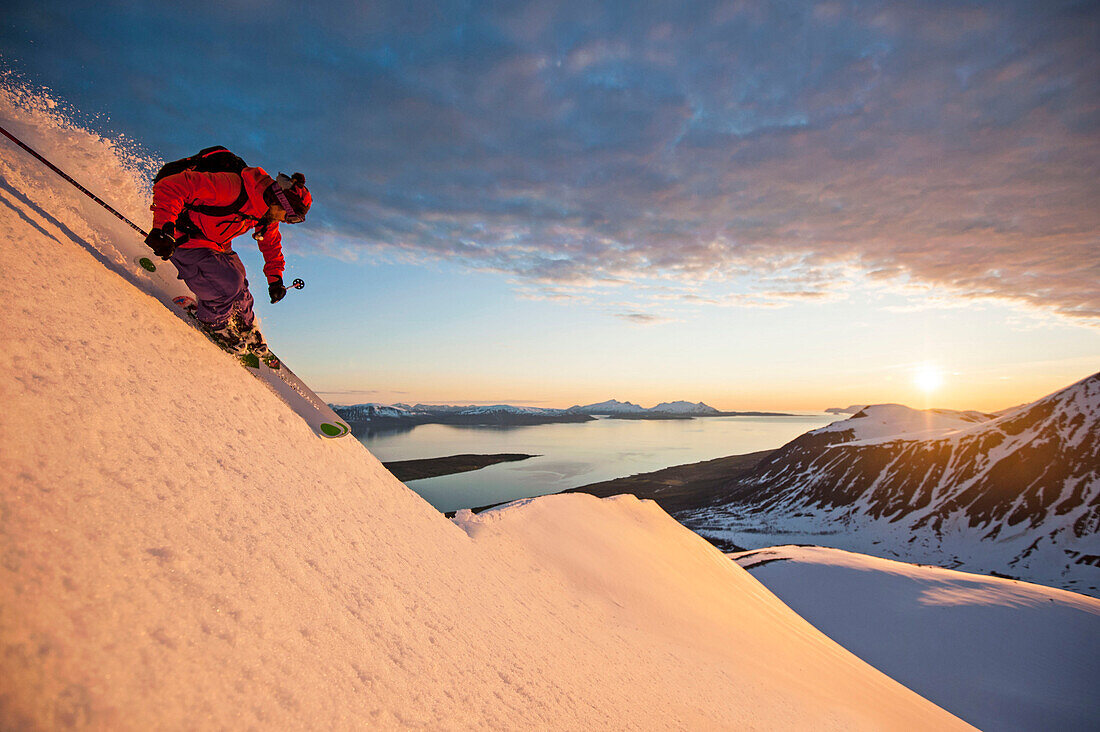 Skifahrer fährt in der Mitternachtssonne ab, Lyngenalpen, Troms, Norwegen