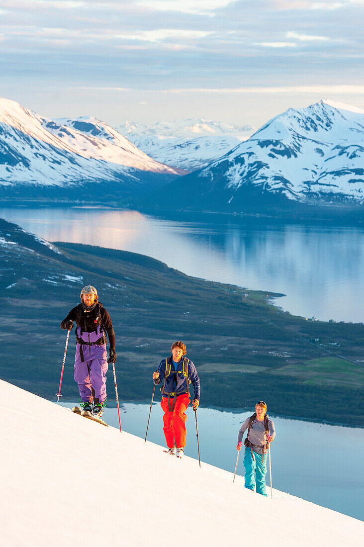 Skifahrer steigen in der Mitternachtssonne auf, Lyngenalpen, Troms, Norwegen