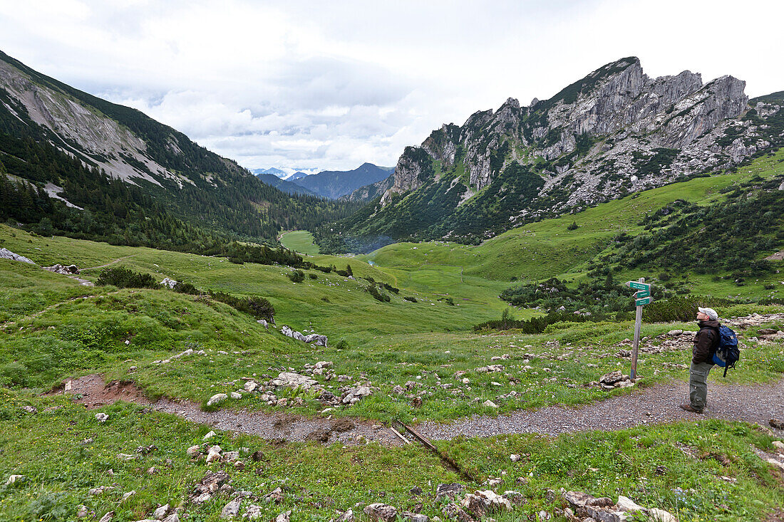 Wanderer liest Wegweiser, Großtiefentalalm, Ruchenköpfe im Hintergrund, Mangfallgebirge, Bayern, Deutschland