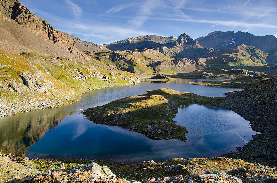 The calm surface of an alpine lake, under rocky ridges, in the early morning in summertime, Valsavarenche, Aosta Valley