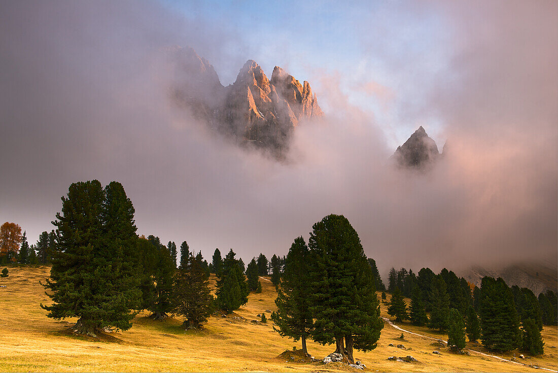 Pastures in autumn, with clouds, and behind them are raising the dolomite's profiles, in the sunset , Dolomites