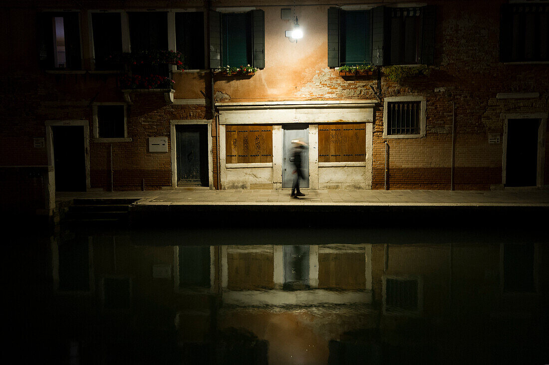Couple walks at night along a canal in Venice, Italy