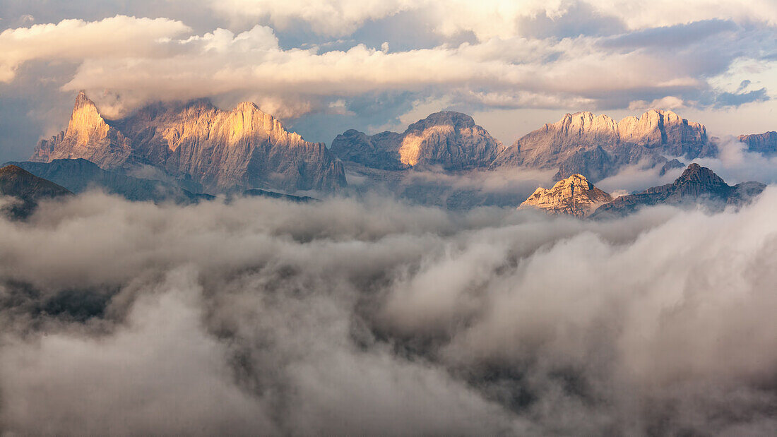 The sunset's light is on fire some dolomite's peak, surrounded by a cloud's sea, Dolomites, Italy