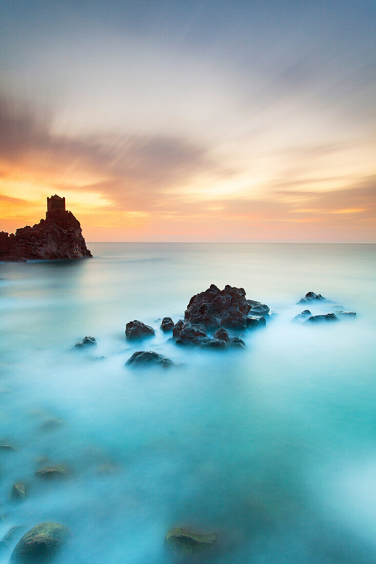 Sea's sunrise, with rocky banks and an ancient tower , Sicily