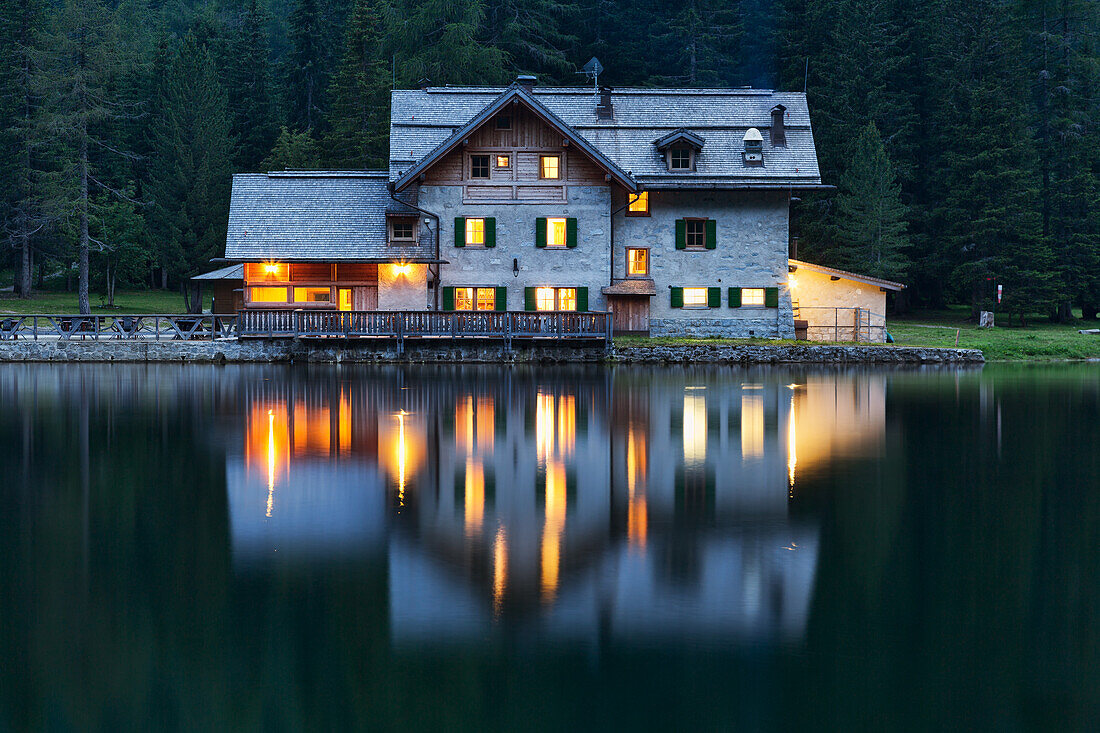 The refuge Nambino is reflected in the lake in the early evening light