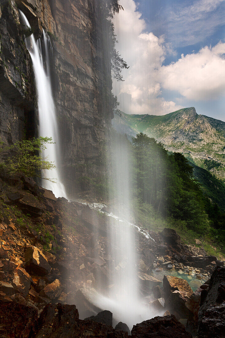 inside of the waterfall of Pis del Pesio with mountain view