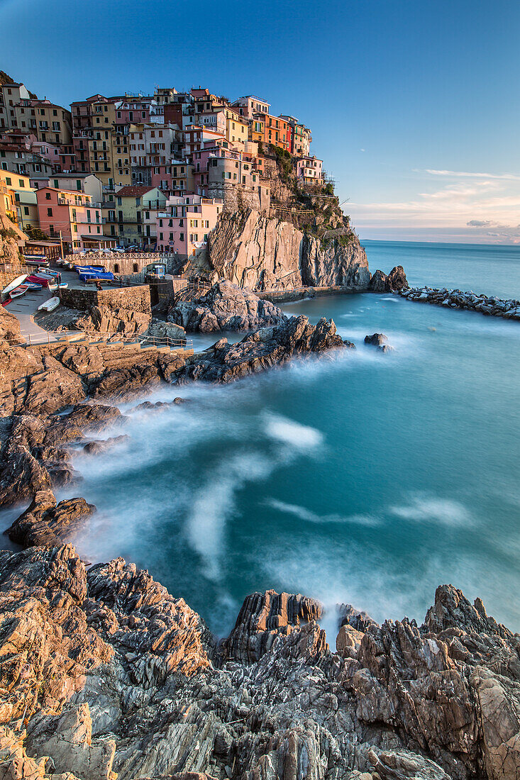 The warm lights of the sunset are painting Manarola, the second smallest village of the five that makes out Cinque Terre. The houses of the village lies on the edge of a cliff along Liguria. This is an UNESCO World Heritage Site, Cinque Terre National Par