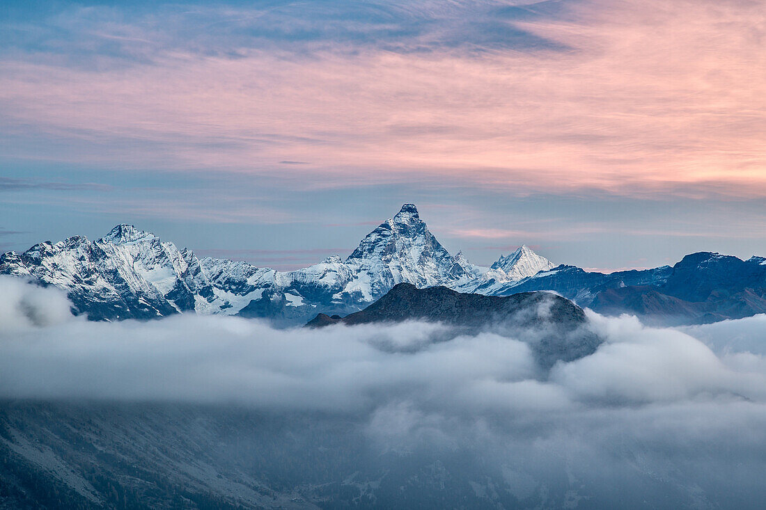 The unmistakable Matterhorn shape colored by the first lights of the sunrise from a peak in the Mont Avic Natural Parc, Aosta Valley, France