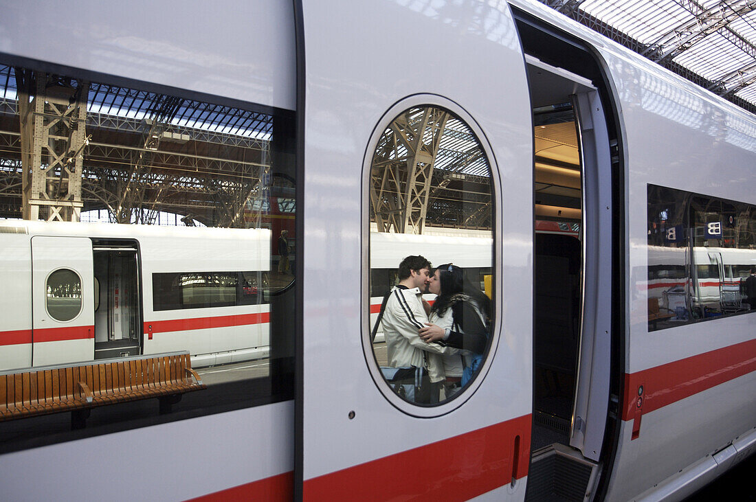 A couple kiss next to  an ICE train at the Leipzig train station in Germany.