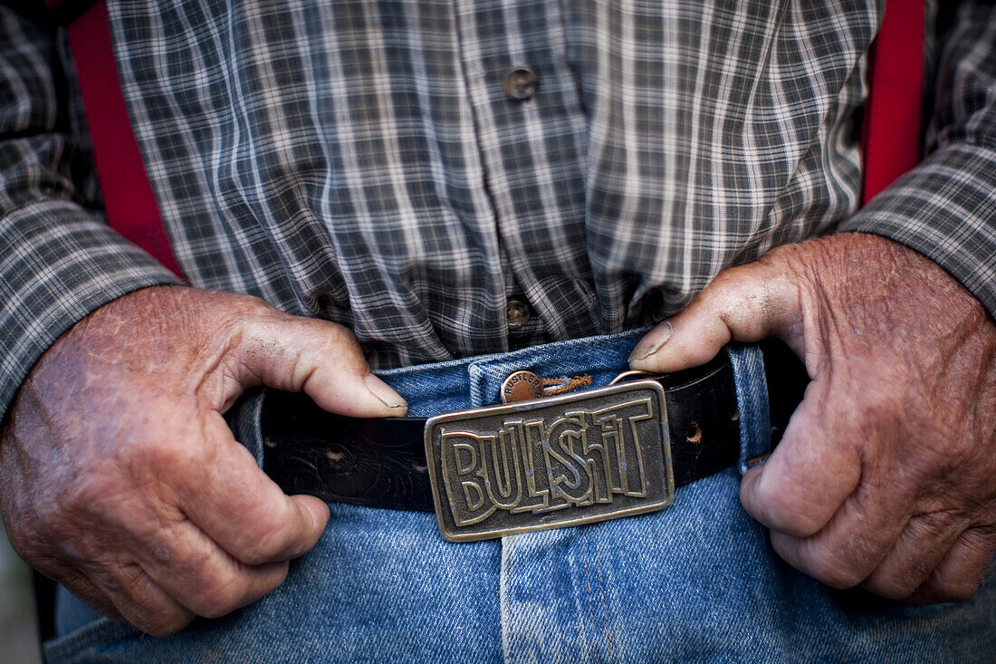 'A rancher wears a belt buckle that reads ''Bullshit''.'