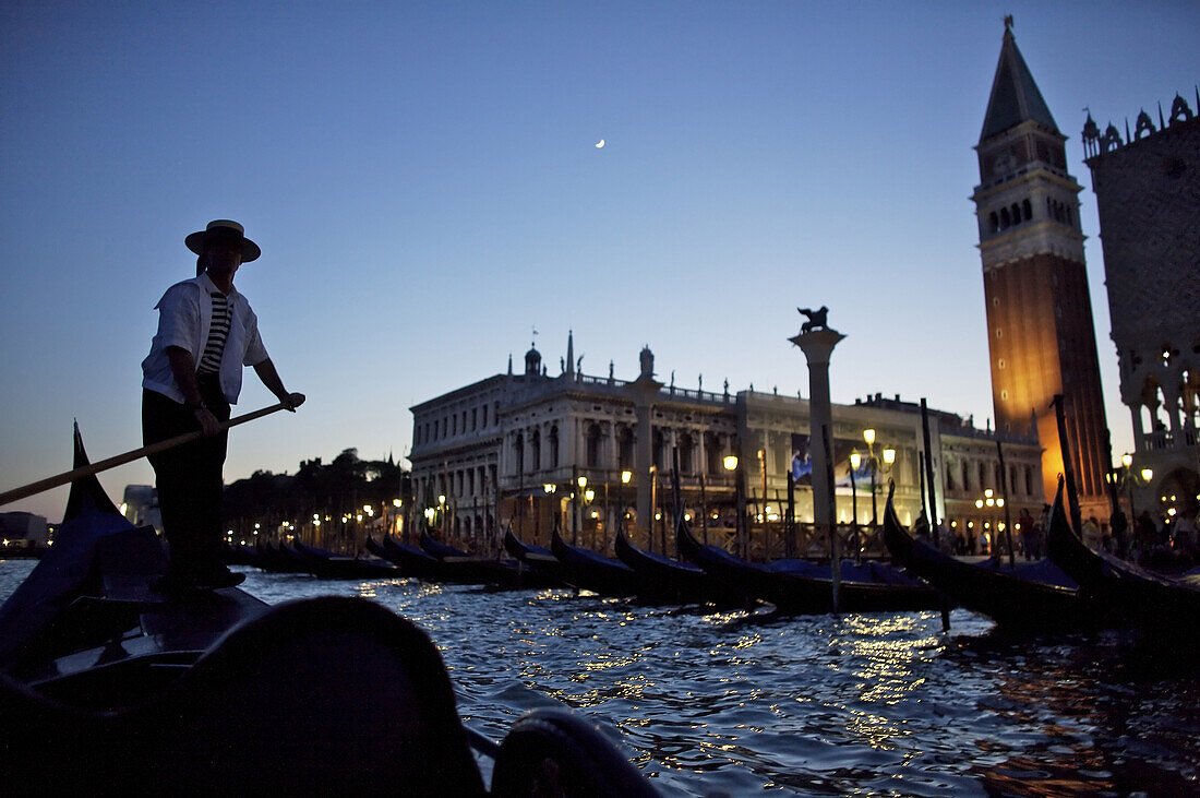 A gondolier navigates just offshore of Venice, Italy, at night.