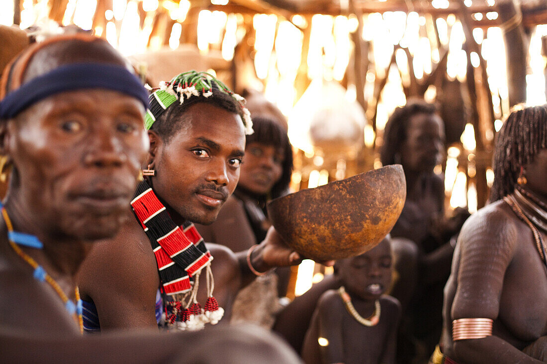 HAMER VILLAGE, OMO VALLEY, ETHIOPIA. Traditional Hamer families gather inside a straw hut to enjoy coffee in the morning.