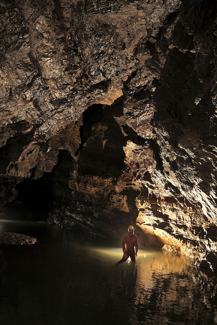 A Russian cave explorer stood in the middle of a large river passage called Lio Mu Shu deep underground in China.