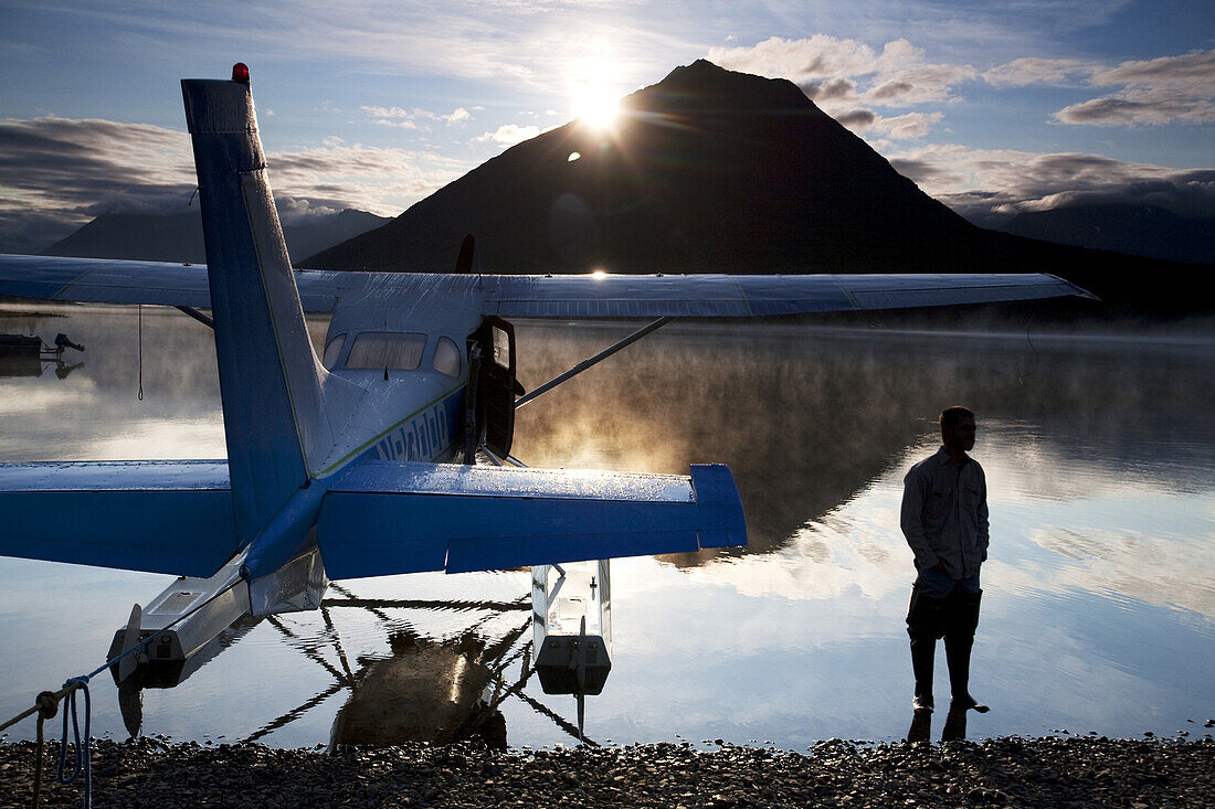A man stands next to a float plane in Twin Lakes in Lake Clark National Park, Alaska.