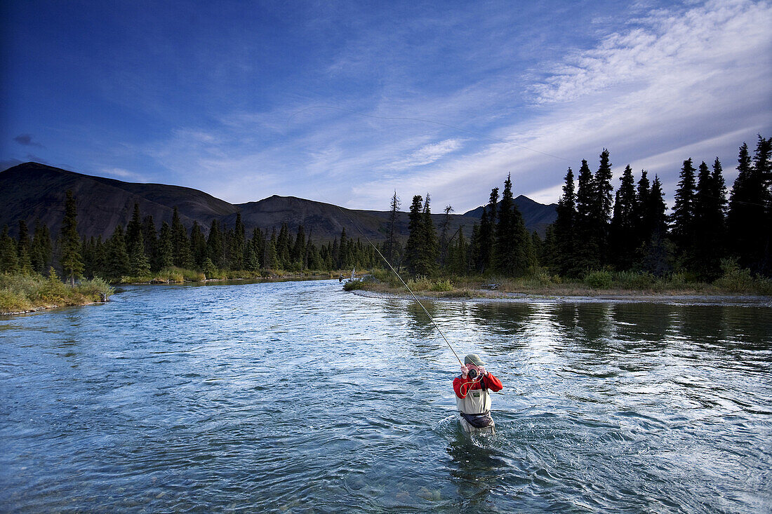 Dan Duane wades in a river in Lake Clark National Park, Alaska to fly fish.
