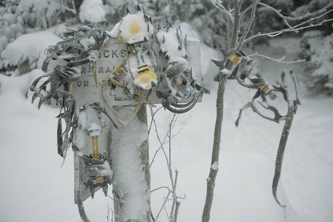 Crampons hang on a trail sign near Gray Knob Cabin at the North end of the Presidential Range and the traditional start of the range traverse.