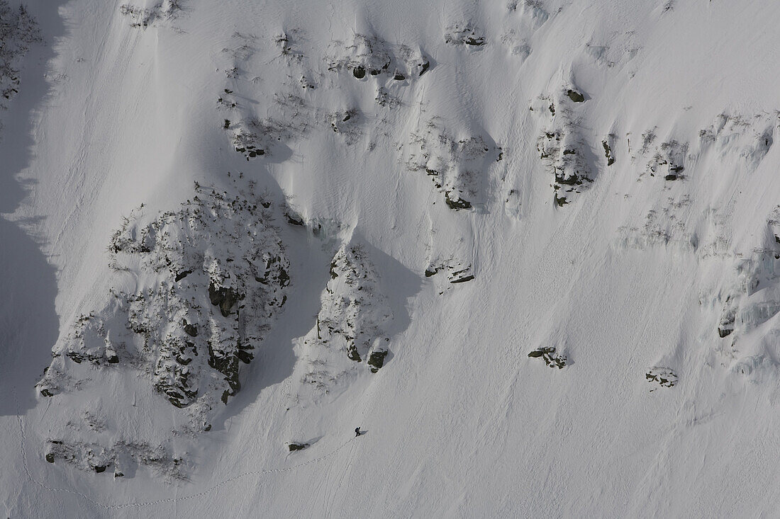 A lone mountaineer crosses underneath some of the gullies on Tuckerman Ravine on the shoulder of Mt. Washington, the highest peak in New England,  and the White Mountains of New Hampshire.