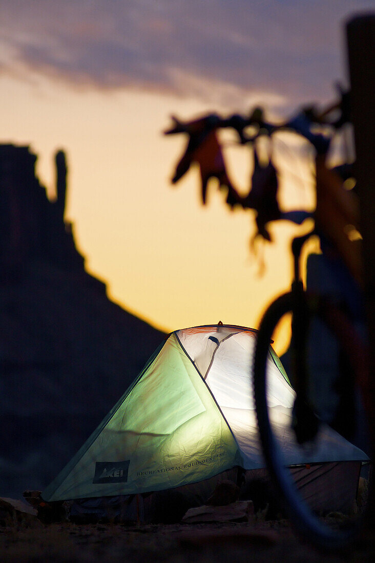 A tent is illuminated at camp on  day two of mountain bike ride of the white rim trail in canyonlands national park, Utah.