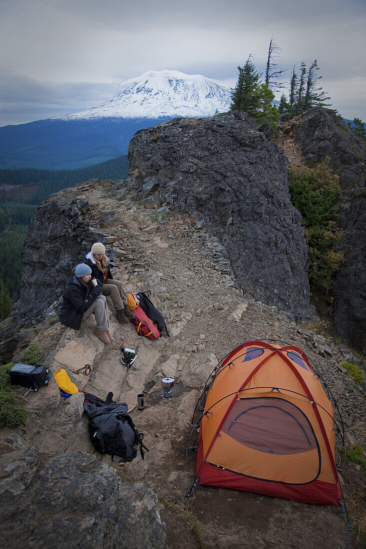 Two young women sit outside their tent while camping along Sleeping Beauty in the Pacific Northwest  Sleeping Beauty - a prominent rock precipice near the southern flanks of Mt Adams one of the Pacific Northwests great day hikes is a great playground for 