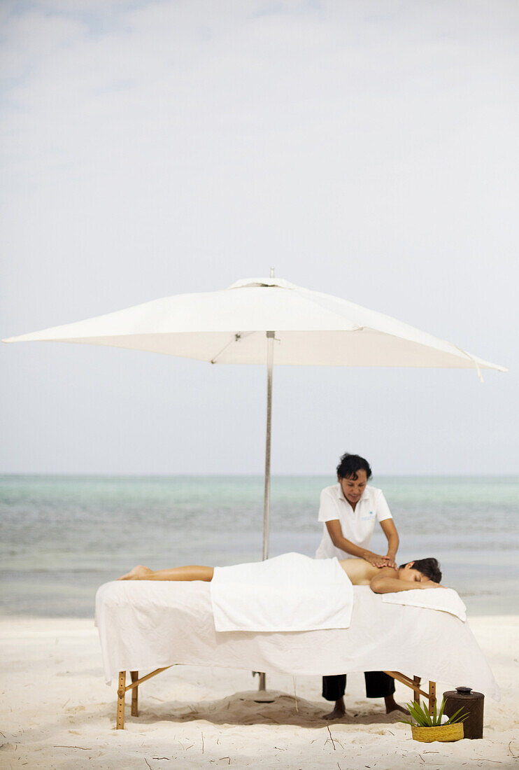 Ambergris Cay, Belize. A woman get a message while on vacation at the beach.