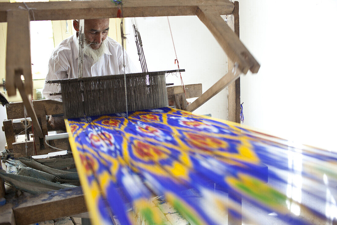 Hotan, Xinjiang, China - September 29, 2009: Senior man weaving colorful silk in a traditional silk factory outside Hotan.