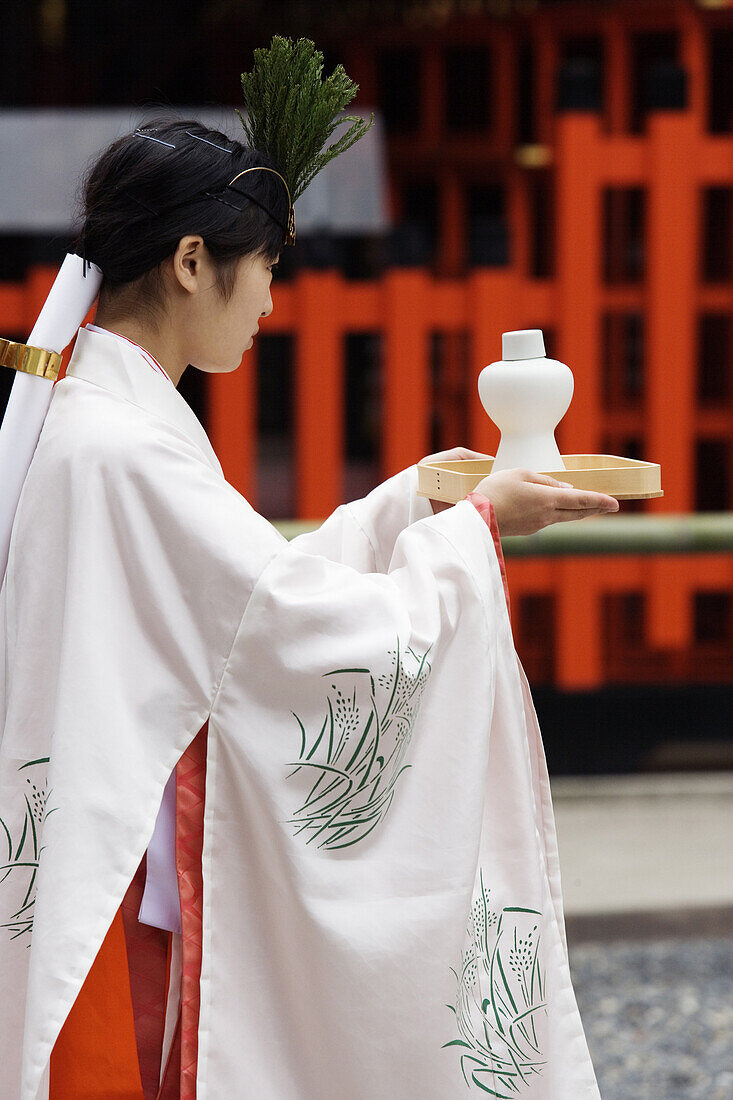 A woman carrying offering in traditional ceremony at the Fushimi Inari Shrine, Kyoto, Japan.