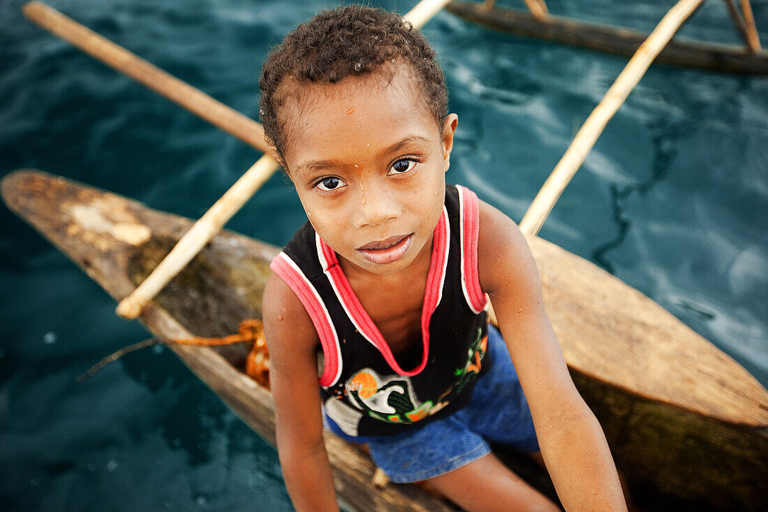 Children on an outrigger canoe at Nimoa Island in the Louisiades Archipelago, Papua New Guinea.