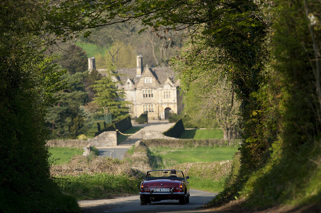 Tony Merrygold, owner of The Open Raod Classic Car Hire drives a red MG through Lower Slaughter.