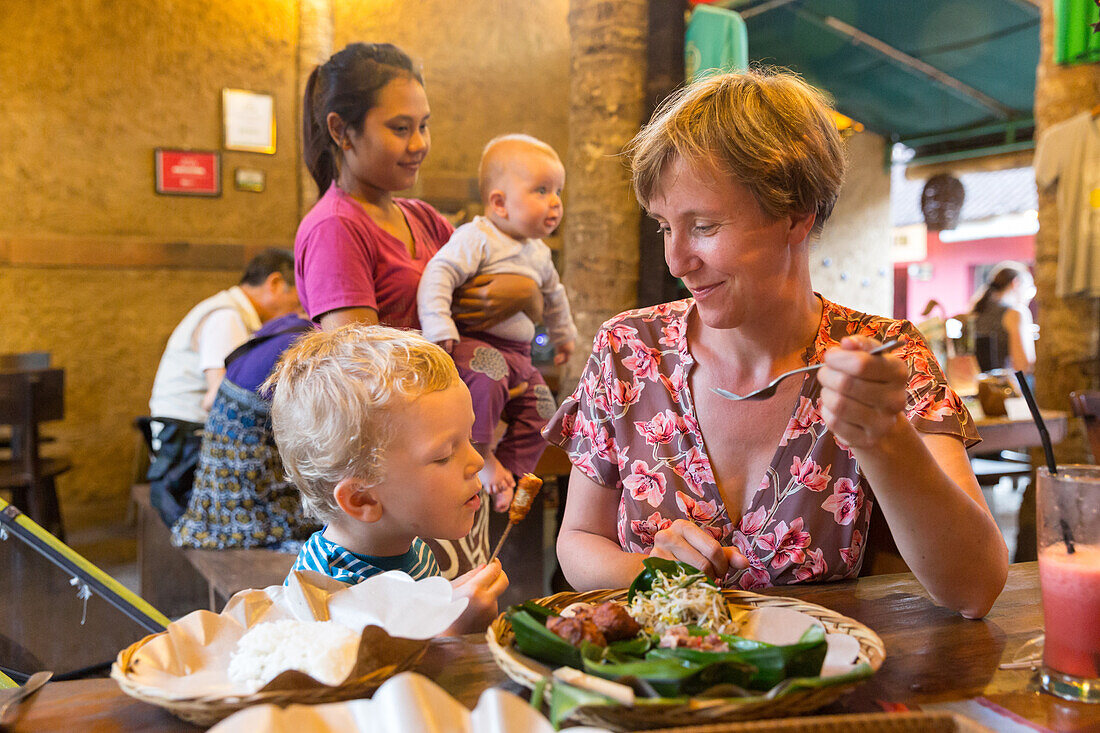 Mother and son eating in a restaurant, traditional Balinese food, dinner, Balinese waitress takes care of baby, 5 months, little boy 3 years old, restaurant Biah Biah, western family, family travel in Asia, parental leave, MR, Ubud, Bali, Indonesia