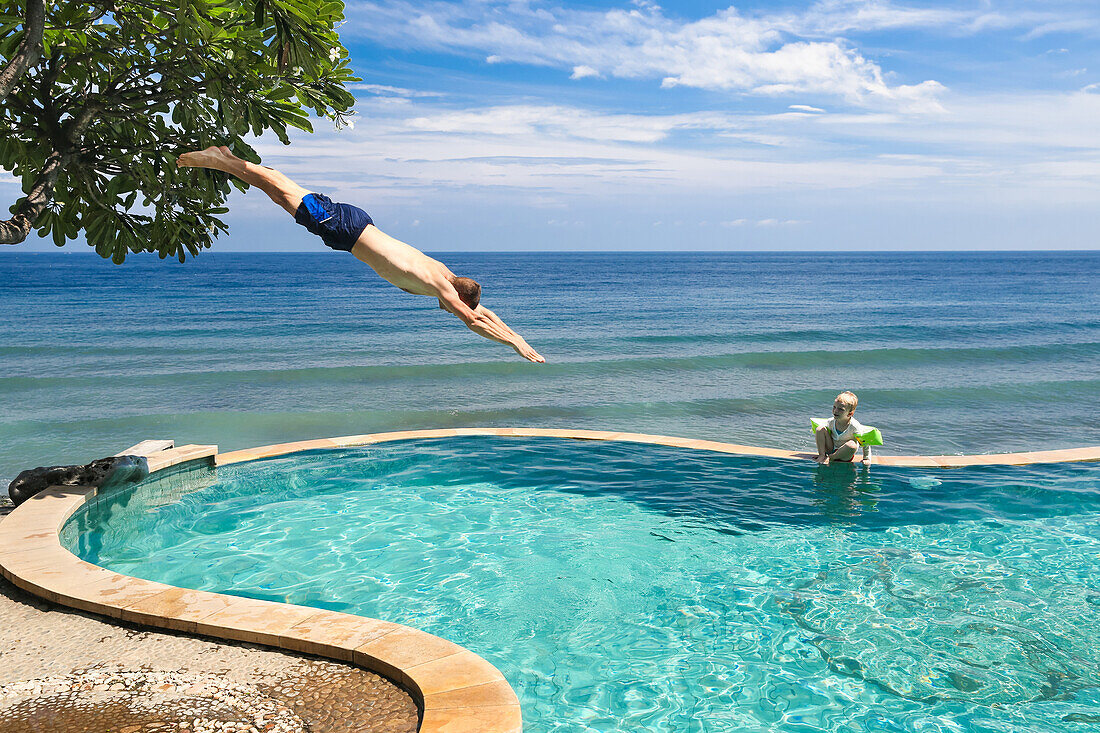 Vater und Sohn im Swimming Pool, Papa springt ins Wasser, Kopfsprung, vom Baum, Meer, edler Überlaufpool, Luxus, Urlauber, Touristen, Baum, Junge 3 Jahre alt, blauer Himmel, Paradies, Elternzeit in Asien, Europäer, Deutsche, Westler, Familie, MR, Amed, Ba