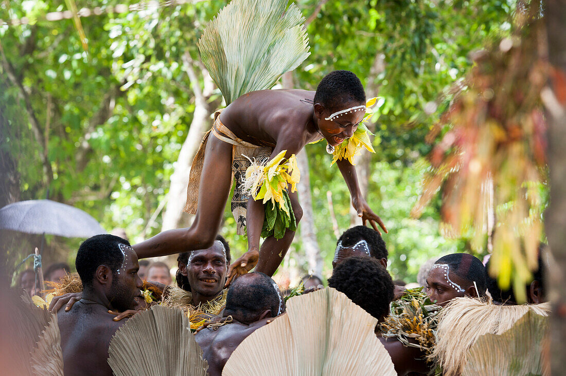Ein Junge wird während einer traditionellen Tanzvorführung über die Köpfe der Erwachsenen gehoben, Insel Nendo, Santa Cruz-Inseln, Salomonen, Südpazifik