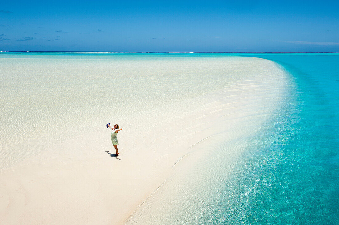 A woman opening her arms in delight on a sand bank at One Foot Island in Aitutaki Lagoon, Aitutaki, Cook Islands, South Pacific