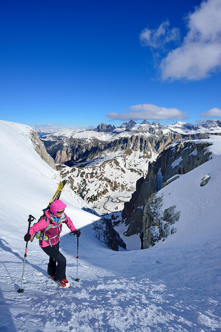 Frau auf Skitour steigt durch enges Couloir im Val Culea auf, Geisler im Hintergrund, Sella, Sellagruppe, Dolomiten, Südtirol, Italien