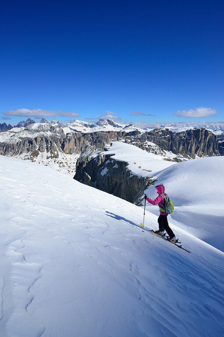 Female back-country skier ascending in Val Culea, Geisler Group in background, Sella Group, Dolomites, South Tyrol, Italy