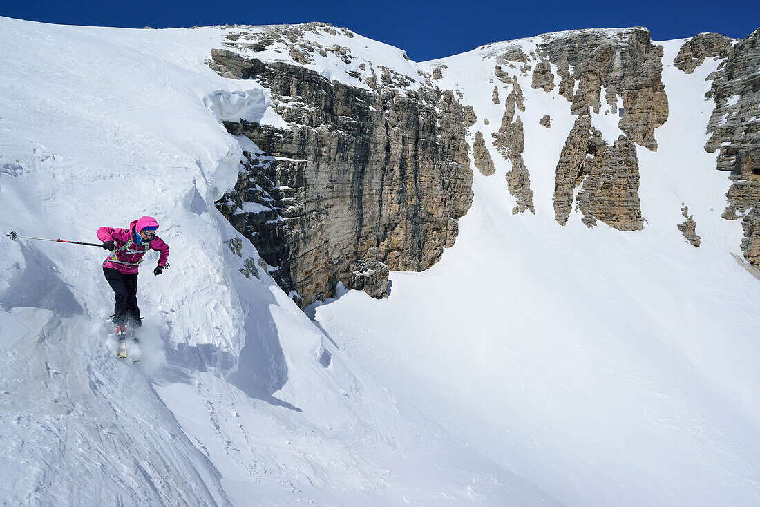 Female back-country skier downhill skiing through Val Pisciadu, Sella Group, Dolomites, South Tyrol, Italy