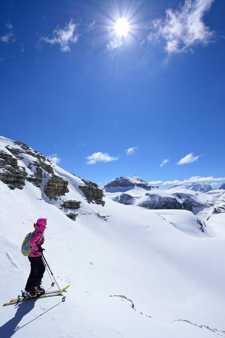 Frau auf Skitour betrachtet Sellagruppe mit Piz Boe, Sellagruppe, Dolomiten, Südtirol, Italien