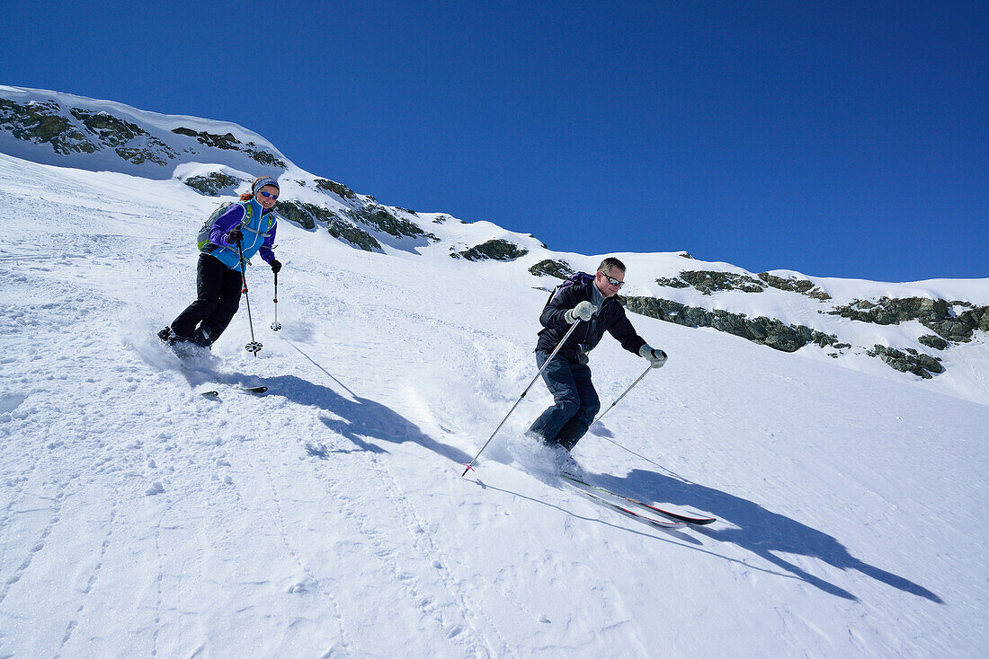 Two back-country skiers downhill skiing from Piz Lagrev, Oberhalbstein Alps, Engadin, Canton of Graubuenden, Switzerland