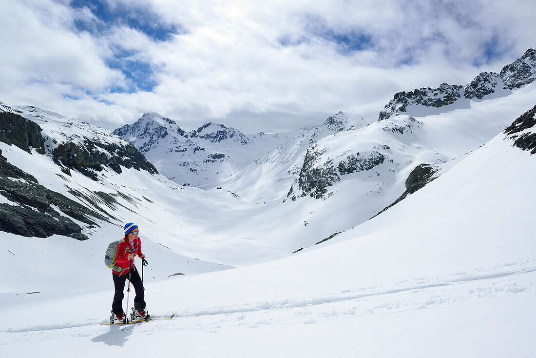 Female back-country skier ascending to Piz d Err, Piz Bever in background, Engadin, Canton of Graubuenden, Switzerland