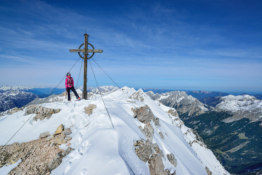 Woman standing beside summit cross of Birkkarspitze, Karwendel range, Tyrol, Austria
