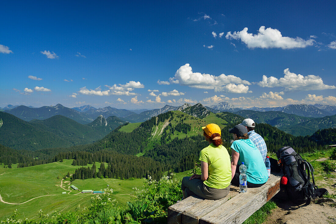 Hikers sitting on a bench at summit of Seekarkreuz, Bavarian Prealps, Upper Bavaria, Bavaria, Germany