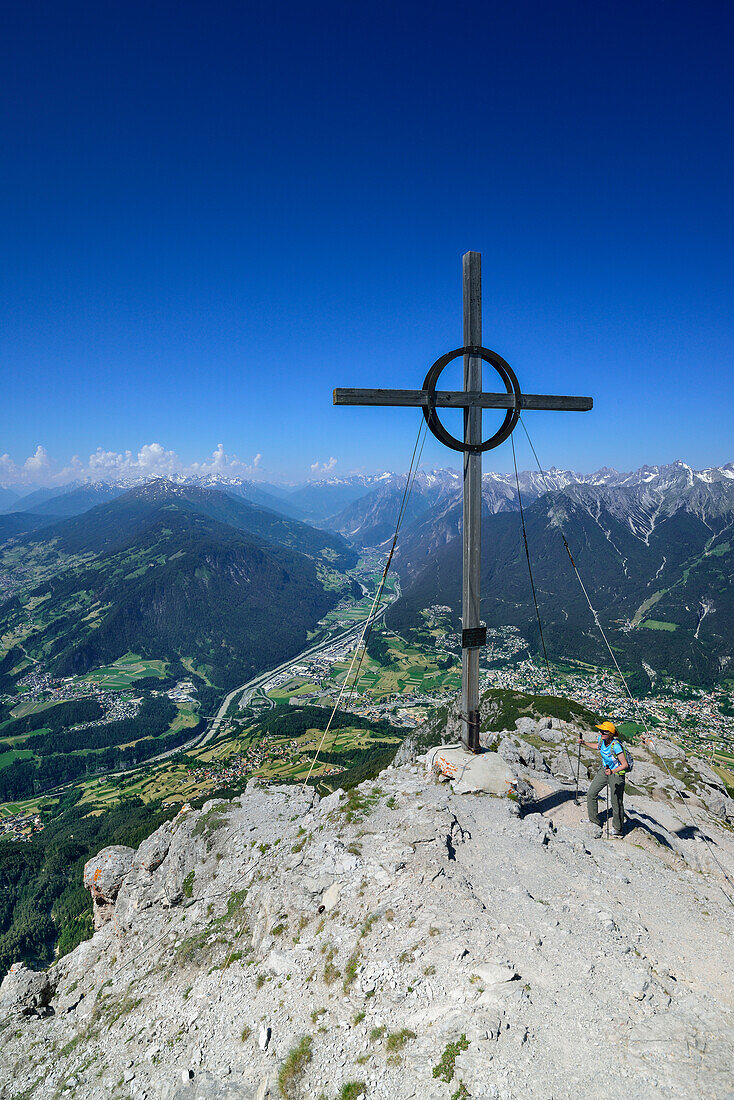 Woman standing beside summit cross on Tschirgant, Mieming Range, Tyrol, Austria