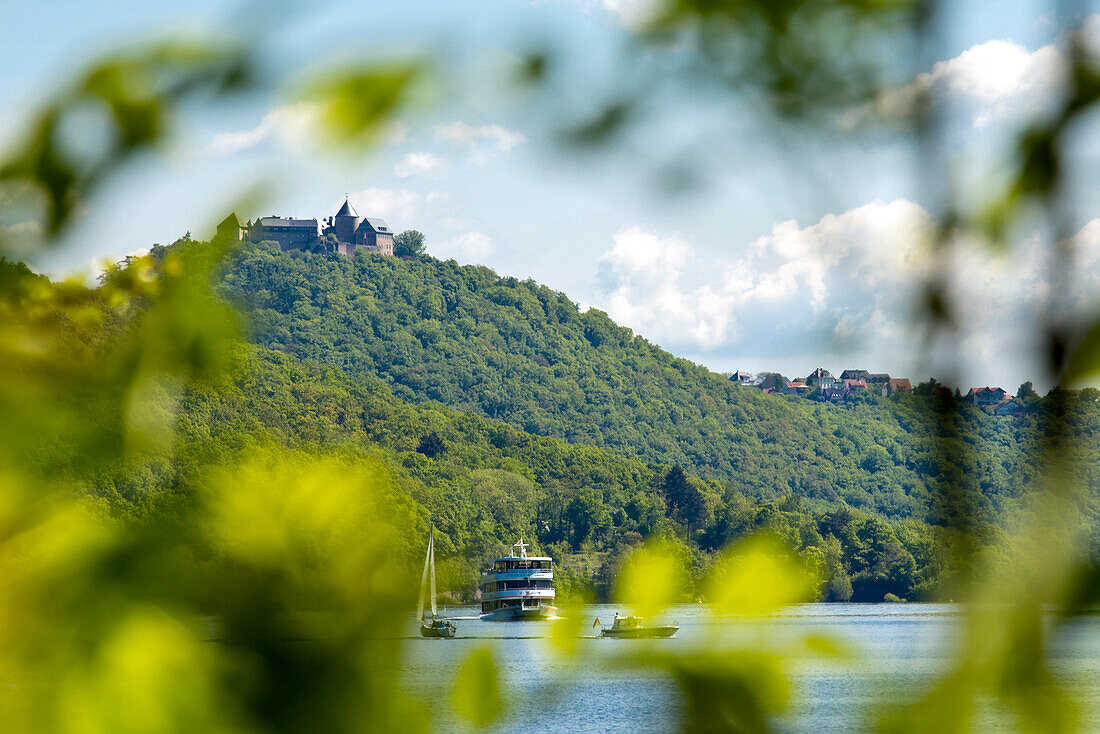 Blick durch Blätter auf Schloss Waldeck mit dem Ausflugsschiff Stern von Waldeck auf dem Edersee im Nationalpark Kellerwald-Edersee, Nordhessen, Hessen, Deutschland, Europa