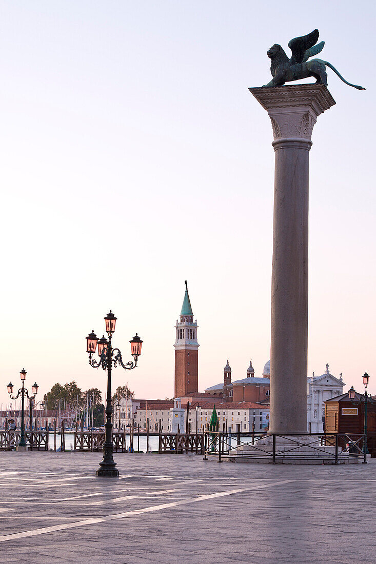 Die große Säule mit dem geflügelten Löwen von San Marco mit Blick zur Insel Isola di San Maggiore mit der Kirche Chiesa di San Maggiore bei Sonnenaufgang, Venedig, Venetien, Italien, Europa