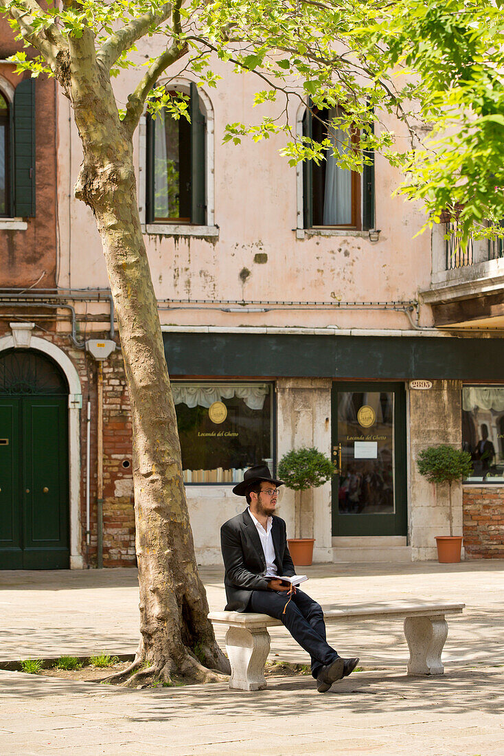 Ein Jude sitzt am Sabbat auf einer Bank unter einem Baum auf dem Campo del Ghetto Nuovo in Ghetto Vecchio, Venedig, Venetien, Italien, Europa