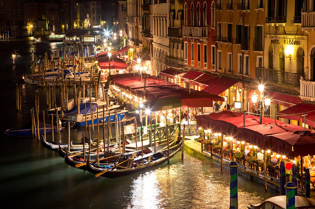View from Rialto bridge to gondolas and restaurants along the Grand Canal at night, Venice, Veneto, Italy, Europe