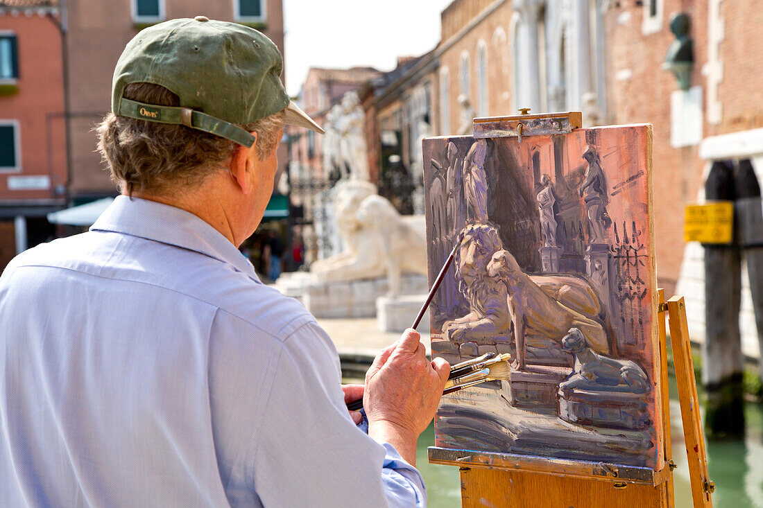 An artist painting the lion sculptures at the Arsenale, Venice, Veneto, Italy, Europe